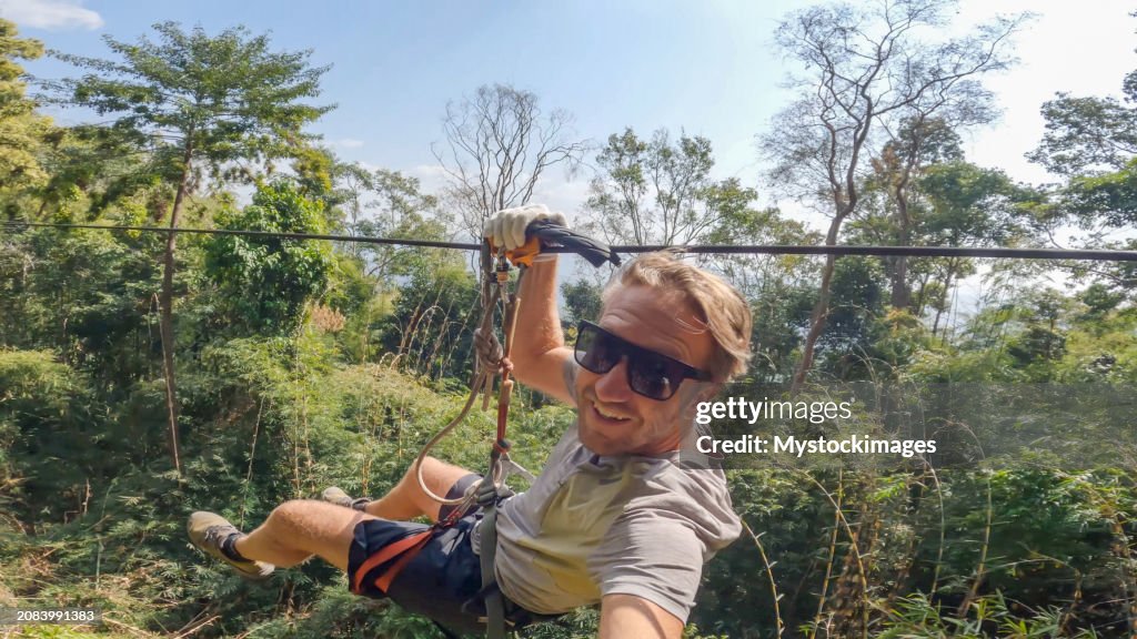 Young man zip lining in the jungle of Laos