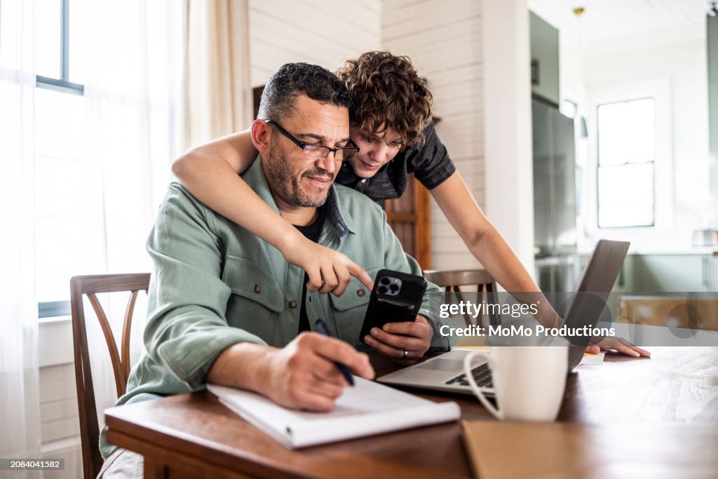 Father working from home with teenage son