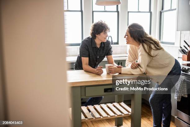 mother and teenage son talking in kitchen - teenage son stock pictures, royalty-free photos & images