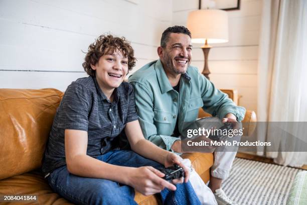 father and teenage son playing video games at home - momo challenge stockfoto's en -beelden