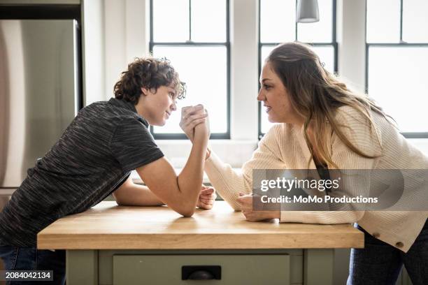 mother and teenage son arm wrestling in kitchen - momo challenge stock pictures, royalty-free photos & images