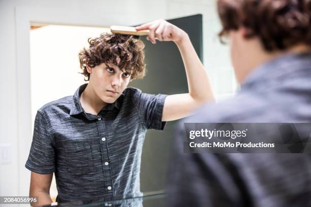 teenage boy brushing hair in bathroom mirror - pimple icon stock pictures, royalty-free photos & images