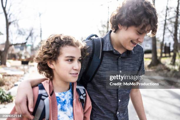 teenage brothers walking down suburban street - momo challenge stockfoto's en -beelden