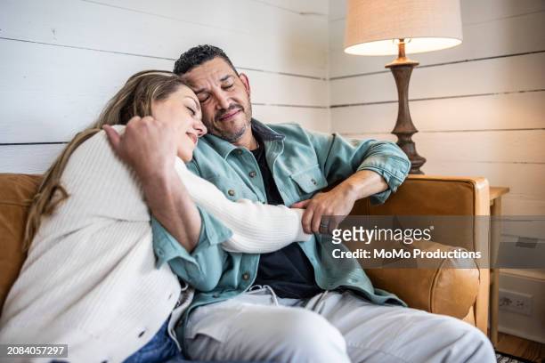 husband and wife snuggling on couch - mature man smiling 40 44 years blond hair stock pictures, royalty-free photos & images