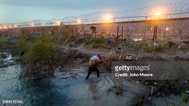 In an aerial view, a Venezuelan immigrant walks through the Rio Grande as he crosses the U.S.-Mexico border on March 13, 2024 in El Paso, Texas. The...