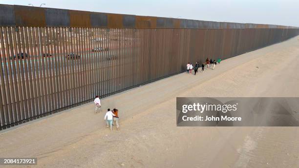 In an aerial view, immigrants walk along the U.S.-Mexico border fence on March 13, 2024 in El Paso, Texas. The border between the two nations...