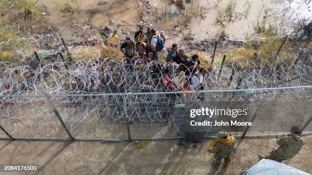 In an aerial view, Texas National Guard soldiers prevent immigrants from passing through razor wire at the U.S.-Mexico border on March 13, 2024 in El...