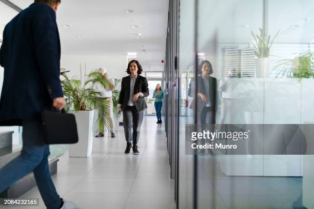 colleagues greeting each other in the office hallway - hotel confirmation stock pictures, royalty-free photos & images