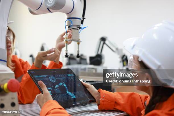 female maintenance engineer working with the digital tablet with the robotic arm and analyst chart data static information of examining in laboratory - mechatronics stockfoto's en -beelden