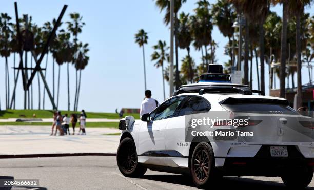 Waymo autonomous self-driving Jaguar taxi drives along Venice Beach on March 14, 2024 in Los Angeles, California. Beginning today, Waymo One is...