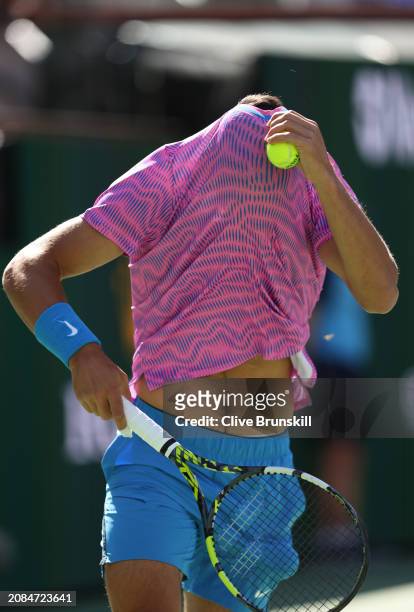 Carlos Alcaraz of Spain hides under his shirt as a swarm of bees invade the court whilst playing against Alexander Zverev of Germany in their...