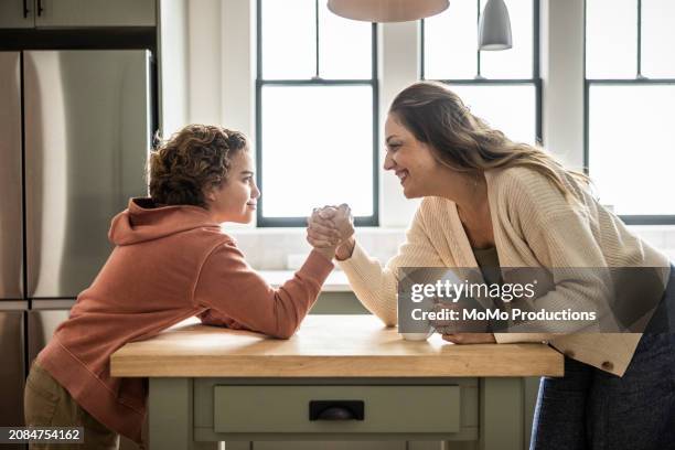 mother and preteen son arm wrestling in kitchen - momo challenge stockfoto's en -beelden