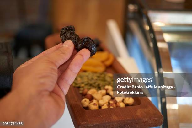 hand holding dried plums - dried plum stock pictures, royalty-free photos & images
