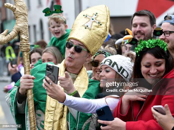 Man dressed in a costume takes photos with members of the crowd as they take part in the St. Patrick's Day parade on March 17, 2024 in Dublin,...