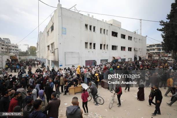 Palestinians gather in front of UN agency for Palestinian refugees building to receive the 5 kg flour aid as the first humanitarian aid convoy in...