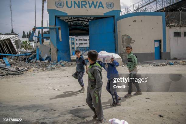 Children carry bags of flour after humanitarian aid was distributed in Gaza City on March 17 amid ongoing battles between Israel and the militant...