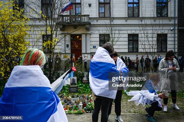 Russian citizens line up to cast their vote as others hold banners and dress as ballet dancers on Russia's election day in front of the Russian...