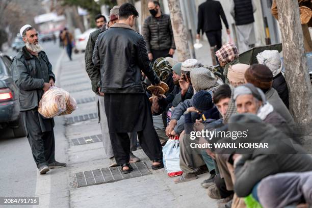 Afghan Muslim devotees distribute free bread to the needy, as they prepare to break their fast during the Islamic holy fasting month of Ramadan in...