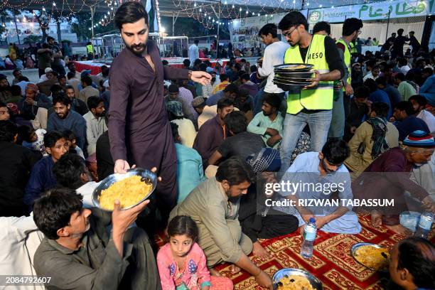 Volunteers distribute plates of biryani to Muslim devotees gathered to break their fast during the Islamic holy fasting month of Ramadan in Karachi...