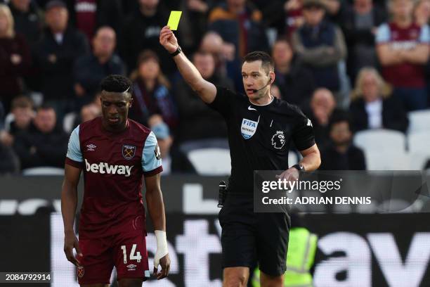 Australian referee Jarred Gillett shows a yellow card to West Ham United's Ghanaian midfielder Mohammed Kudus during the English Premier League...