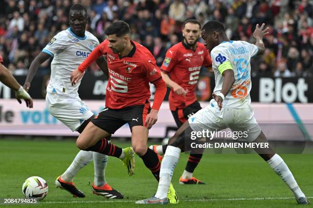 Rennes' French forward Martin Terrier fights for the ball with Marseille's Senegalese French midfielder Pape Gueye and Marseille's French-Central...