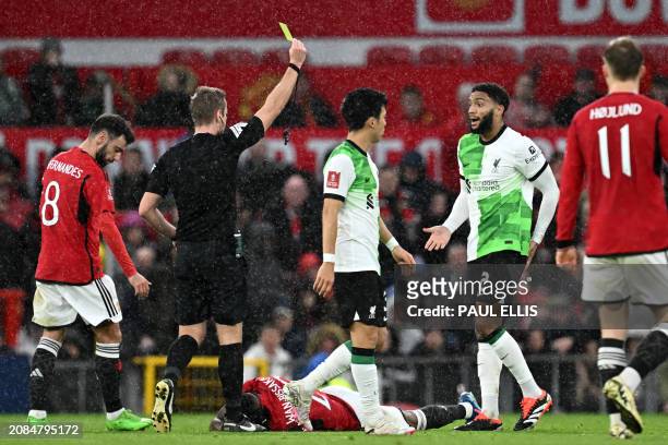 English referee John Brooks shows a yellow card to Liverpool's English defender Joe Gomez during the English FA Cup Quarter Final football match...