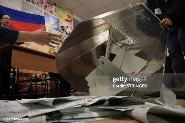 Members of a local electoral commission empty a ballot box at a polling station after polls closed in Russia's presidential election in Simferopol,...