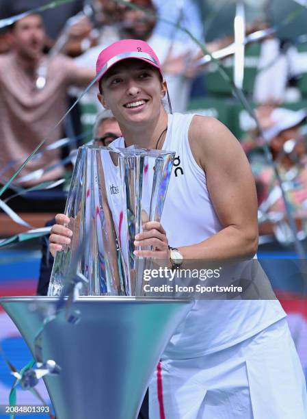 Iga Swiatek holds the BNP Paribas Open championship trophy and streamers fly over her after Swiatek won a WTA finals tennis match played on March 17,...