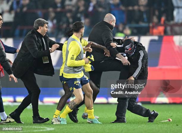 Security officers take measures as a supporter enters to the pitch, after the Turkish Super Lig week 30 football match between Trabzonspor and...