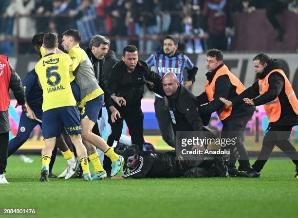 Security officers take measures as a supporter enters to the pitch, after the Turkish Super Lig week 30 football match between Trabzonspor and...