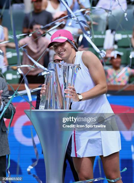 Iga Swiatek holds the BNP Paribas Open championship trophy and streamers fly over her after Swiatek won a WTA finals tennis match played on March 17,...