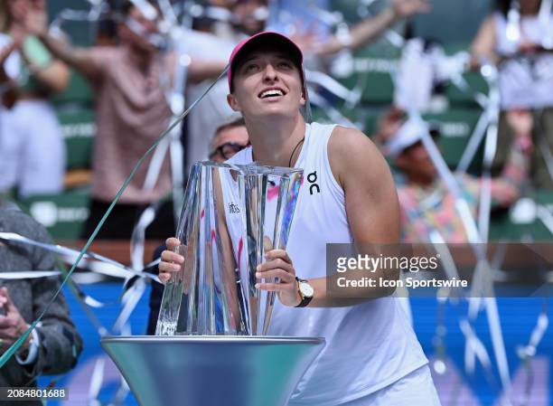 Iga Swiatek holds the BNP Paribas Open championship trophy and streamers fly over her after Swiatek won a WTA finals tennis match played on March 17,...