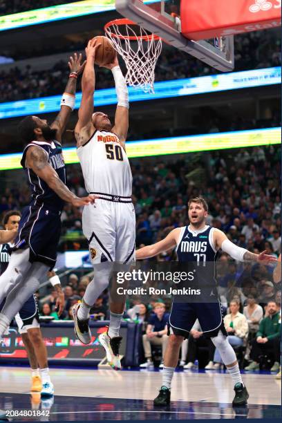 Aaron Gordon of the Denver Nuggets goes up for a slam dunk as Kyrie Irving of the Dallas Mavericks and teammate Luka Doncic defend in the first half...