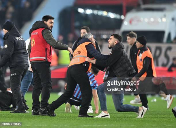 Security officers take measure as supporters enter the pitch, after the Turkish Super Lig week 30 football match between Trabzonspor and Fenerbahce...