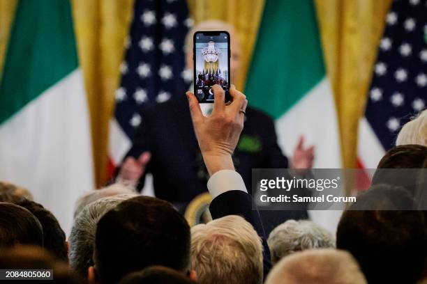 Guest holds up their cell phone to record President Joe Biden as he speaks during a Saint Patrick's Day event with Irish Taoiseach Leo Varadkar in...