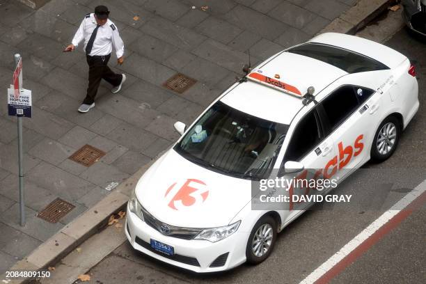 Taxi driver walks past a taxi parked in central Sydney on March 18, 2024. Australian taxi drivers impacted by the rise of ridesharing giant Uber have...