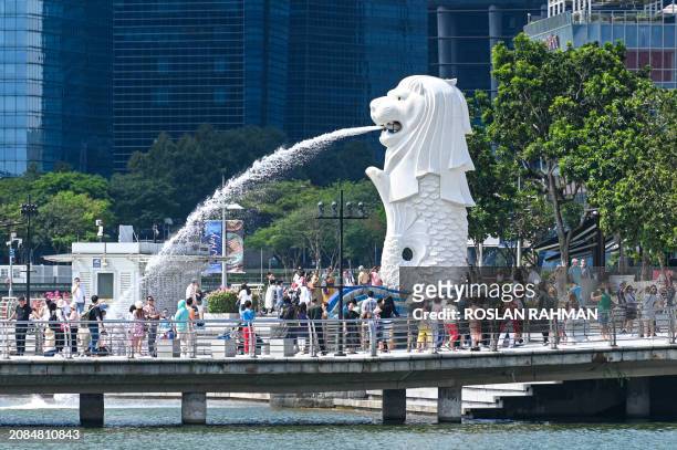 People gather for photograph next to the Merlion statue at Marina bay waterfront in Singapore on March 18, 2024.