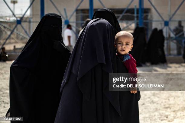 Woman carries her child as she walks towards the fence at the al-Hol camp in Syria's northeastern Al-Hasakah Governorate, on October 10, 2023. The...