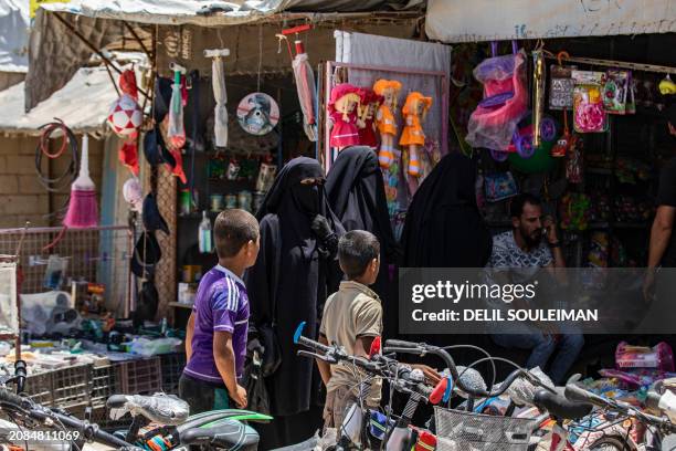 Women and children stand outside a toy shop at the al-Hol camp in Syria's northeastern Al-Hasakah Governorate, on October 10, 2023. The al-Hol camp...