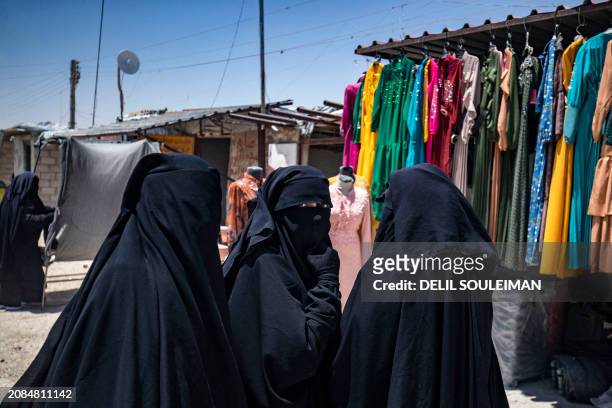Women walk past a garment shop at the al-Hol camp in Syria's northeastern Al-Hasakah Governorate, on October 10, 2023. The al-Hol camp is the largest...