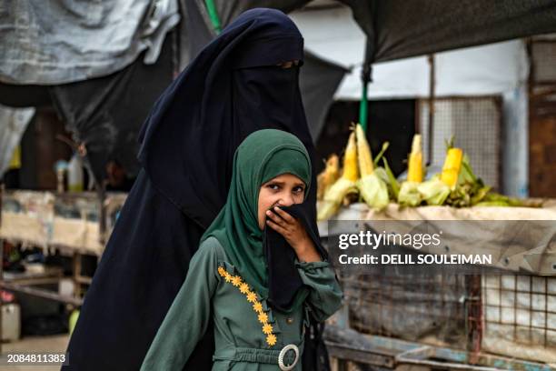 Woman and her daughter walk past a shop at the al-Hol camp in Syria's northeastern Al-Hasakah Governorate, on October 10, 2023. The al-Hol camp is...