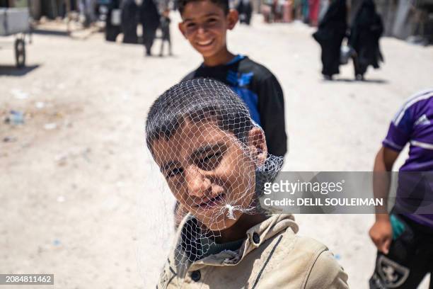 Boy poses with fishnet bag on his head at the al-Hol camp in Syria's northeastern Al-Hasakah Governorate, on October 10, 2023. The al-Hol camp is the...