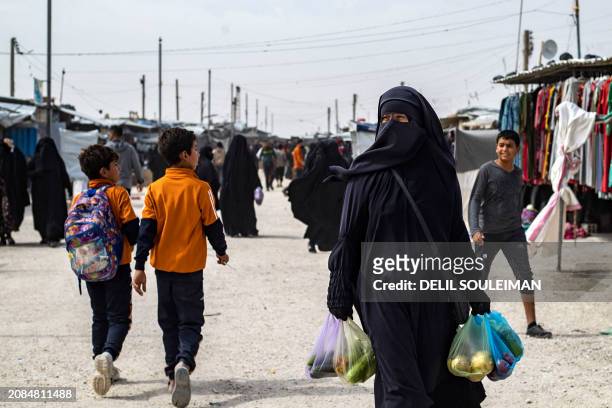 Women carries bags of produce at the al-Hol camp in Syria's northeastern Al-Hasakah Governorate, on October 10, 2023. The al-Hol camp is the largest...