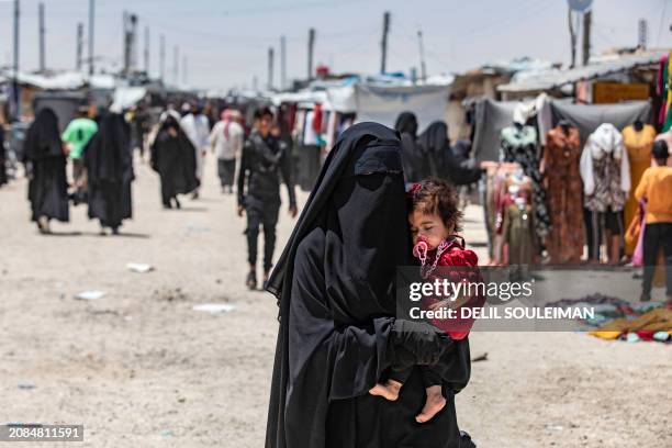 Woman carries a child as she walks through the al-Hol camp in Syria's northeastern Al-Hasakah Governorate, on October 10, 2023. The al-Hol camp is...