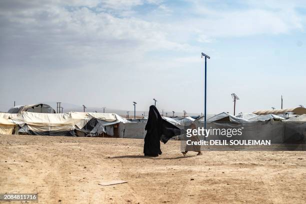 Woman and her daughter walk past tents at the al-Hol camp in Syria's northeastern Al-Hasakah Governorate, on October 10, 2023. The al-Hol camp is the...