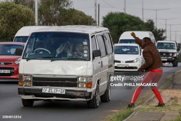 Passengers in a minibus taxi take cover as a protester throws a stone at South African Police Service officers during a service delivery protest in...