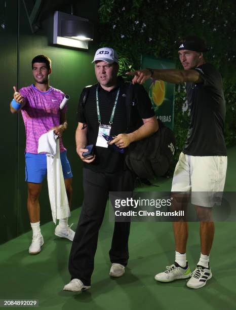 Carlos Alcaraz of Spain and Alexander Zverev of Germany watch on a TV monitor with ATP Trainer Clay Sniteman in the players tunnel after running in...