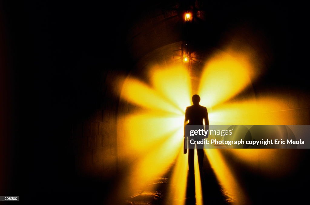 SILHOUETTE OF MAN IN TUNNEL WITH LIGHTS