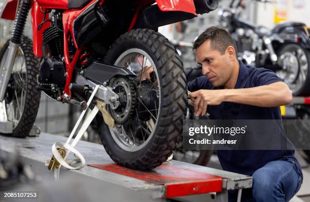 mechanic installing a tire on a motorcycle at a repair shop - bike tyre stock pictures, royalty-free photos & images
