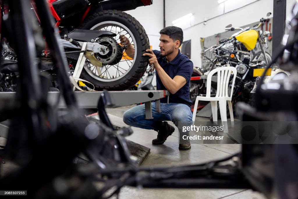 Mechanic installing a wheel on a motorcycle at a repair shop